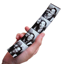 Hand holding a classic black and white photobooth strip with 4 couple photos