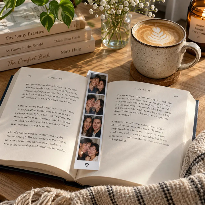 Photobooth strip used as a bookmark inside an open book on a wooden desk